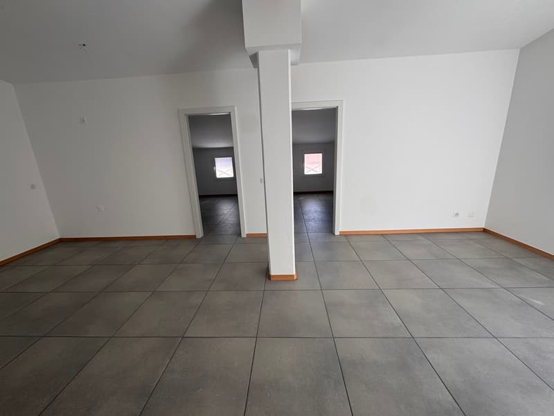 Empty room with white walls, gray tiled floor, two doors, and windows