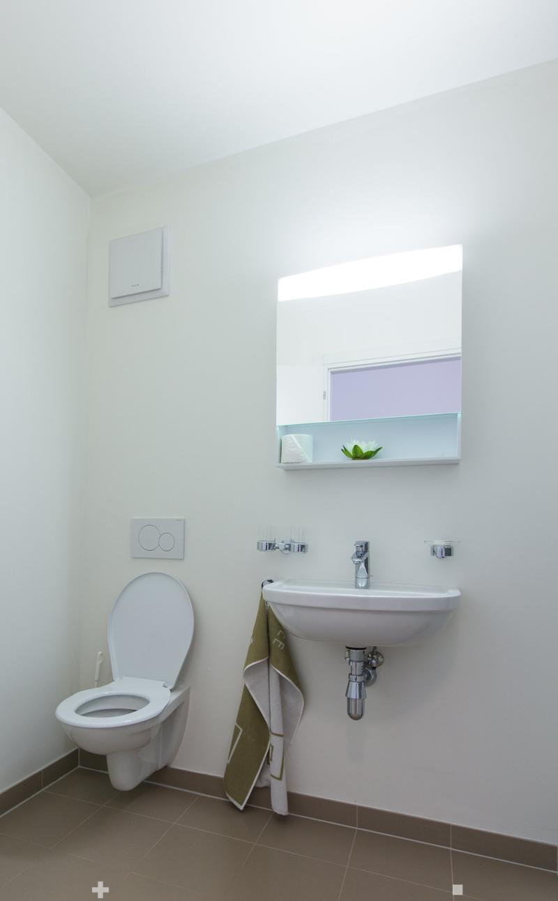 White toilet, sink with faucet, wall-mounted cabinet, tiled floor