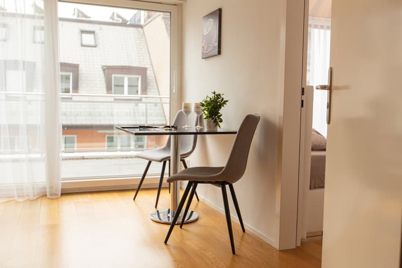 small dining area with two chairs, table, window with a view, potted plant, decorative items
