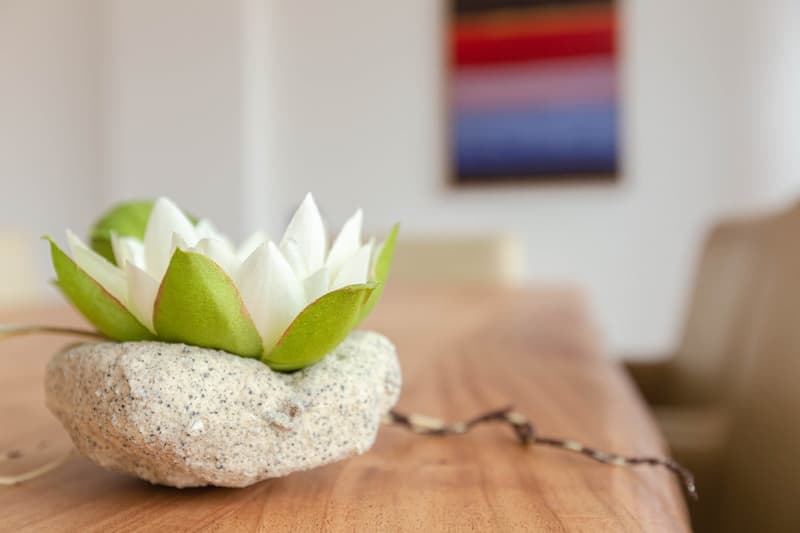 Decorative flower arrangement on a stone planter, wooden table, and a colorful abstract painting on the wall