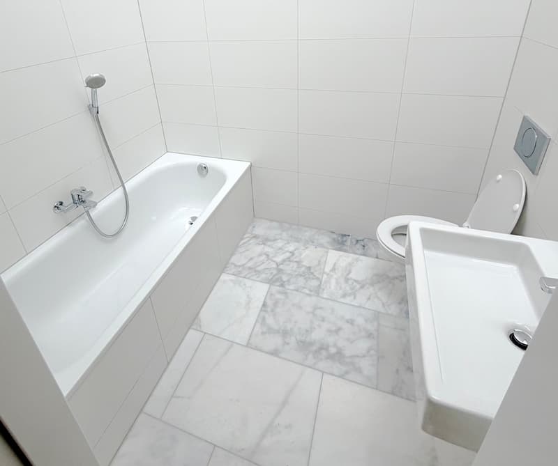 Bathroom with bathtub, toilet, sink, and marble flooring