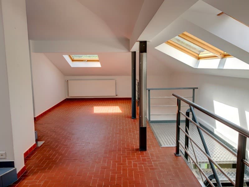 Staircase, white walls, red brick floor, wooden beams, metal railing, skylights, a radiator.