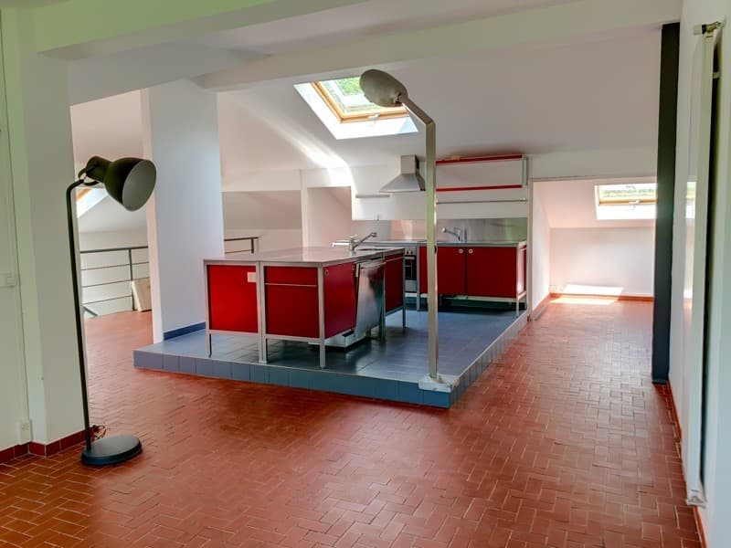 Open kitchen layout with island, red cabinets, stainless steel countertops, modern appliances, bright skylights