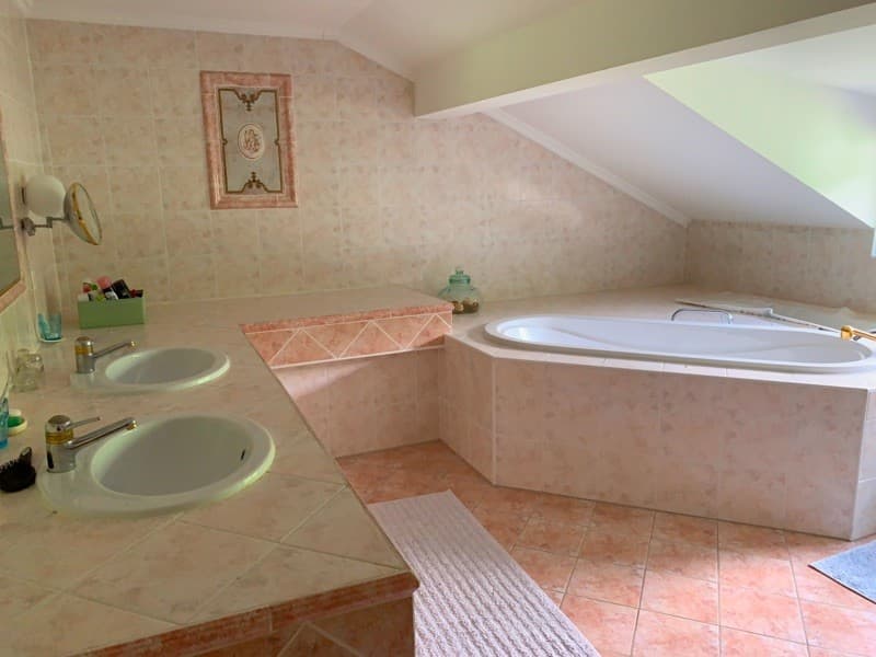 Pink tiles, bathtub, double sink, vanity with mirror, decorative objects, sloped ceiling