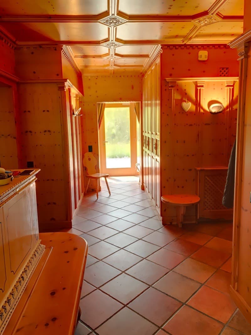 Wooden walls, tiled floor, wooden chair, stool, cabinet, open door to another room with curtains