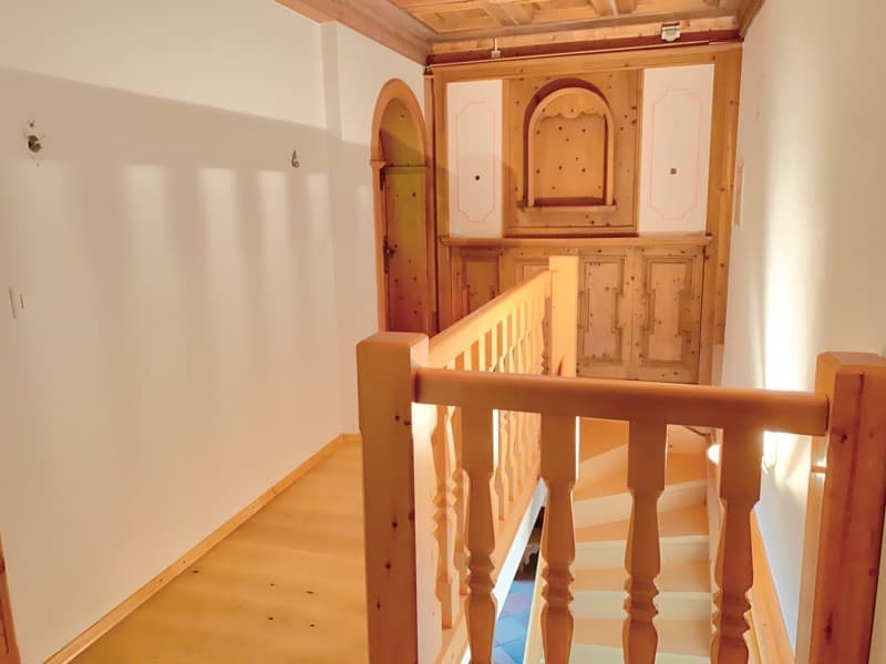 wooden stairs, wooden flooring, wooden walls, white walls, ceiling beams, wooden handrail