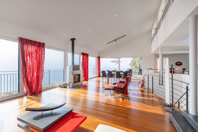 modern open space with fireplace, large glass windows, balcony with railings, hardwood floors