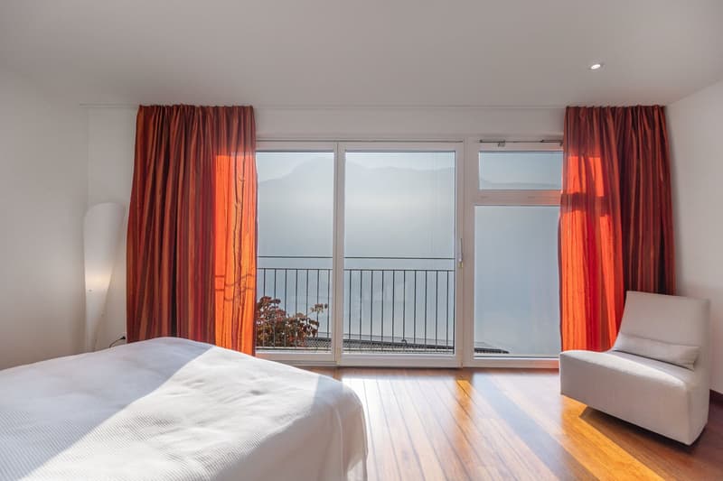 white bed, white chair, white curtains, glass door with balcony