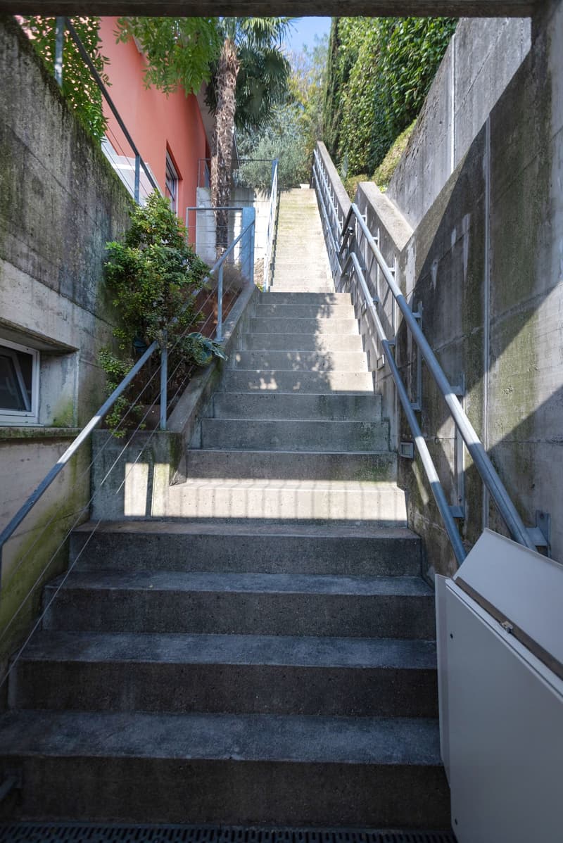 Exterior stairs with metal railing, concrete steps, access ramp