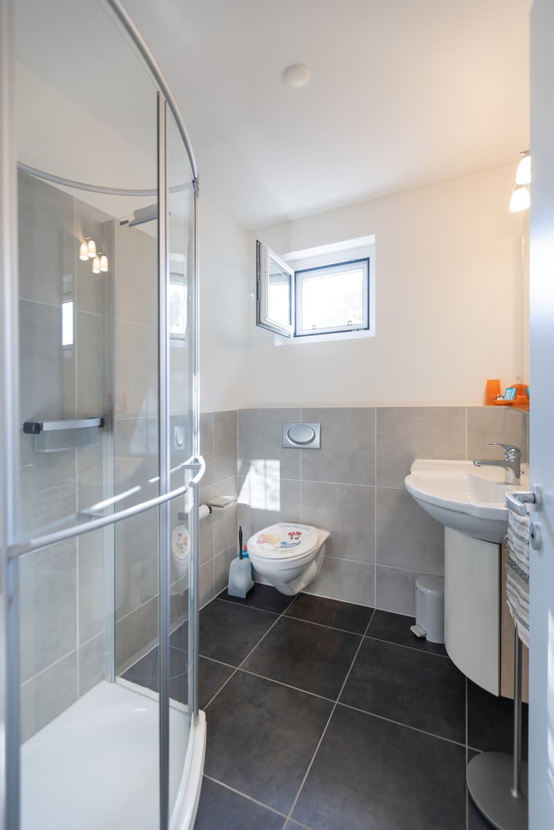 modern bathroom with glass walk-in shower, toilet, sink, pedestal, small window