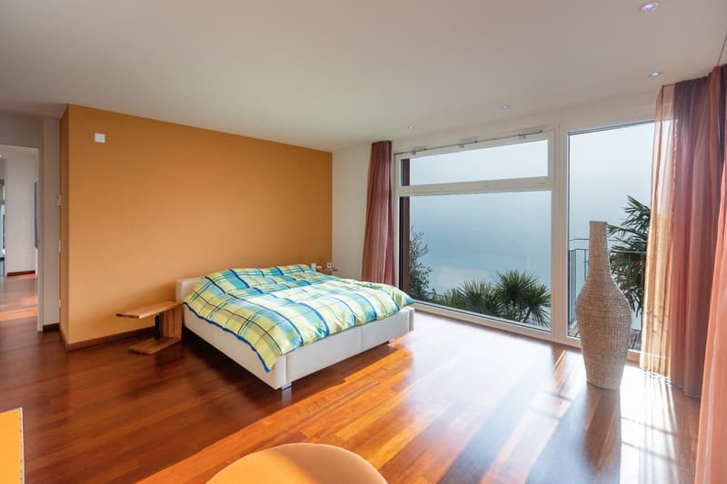 yellow walls, large window, view of landscape, hardwood floor, bed with colorful blanket, bedside table, large vase