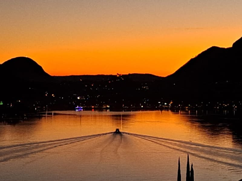 Sunset over the lake with boats and cityscape