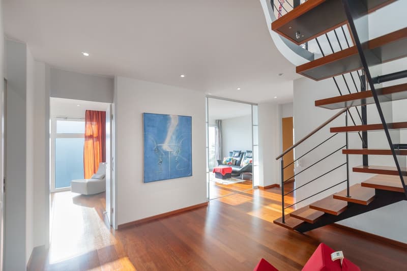 open layout, wooden floor, white walls, staircase, artwork on wall, living room with lounge and decor, glass sliding door, skylight