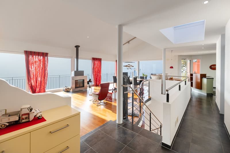 open living space with balcony, large windows, fireplace, glass door, staircase, large skylight