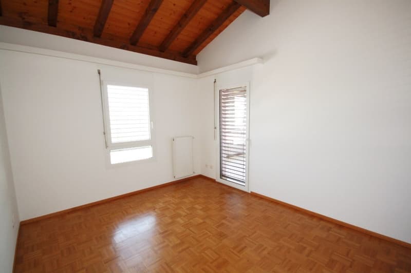 Empty room with white walls, wooden flooring, windows with shutters, white radiator