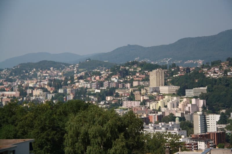 Hill city, multiple buildings, mountains in the background