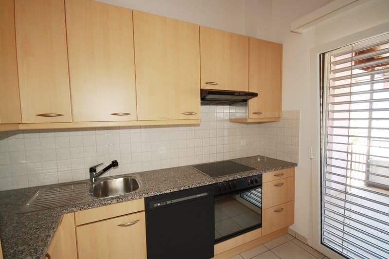 modern kitchen with wooden cabinets, granite countertop, black appliances, stainless steel sink, and white tiles