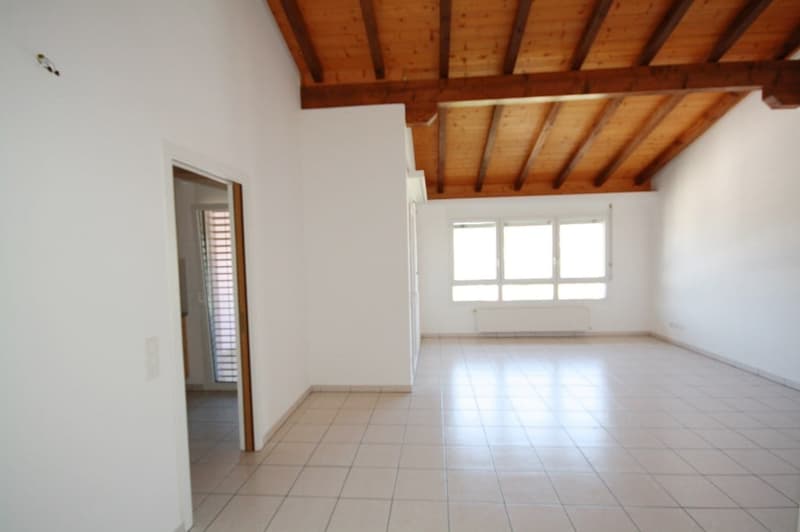 Empty room with white walls, tiled floor, wooden ceiling, door, and window.