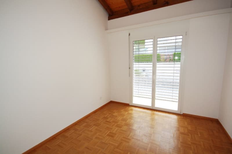 Empty room with white walls, wooden parquet floor, white ceiling, sliding door