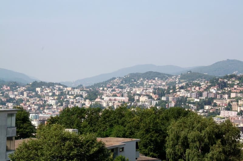 View of a city from a high floor building, buildings, trees, mountains, mountains