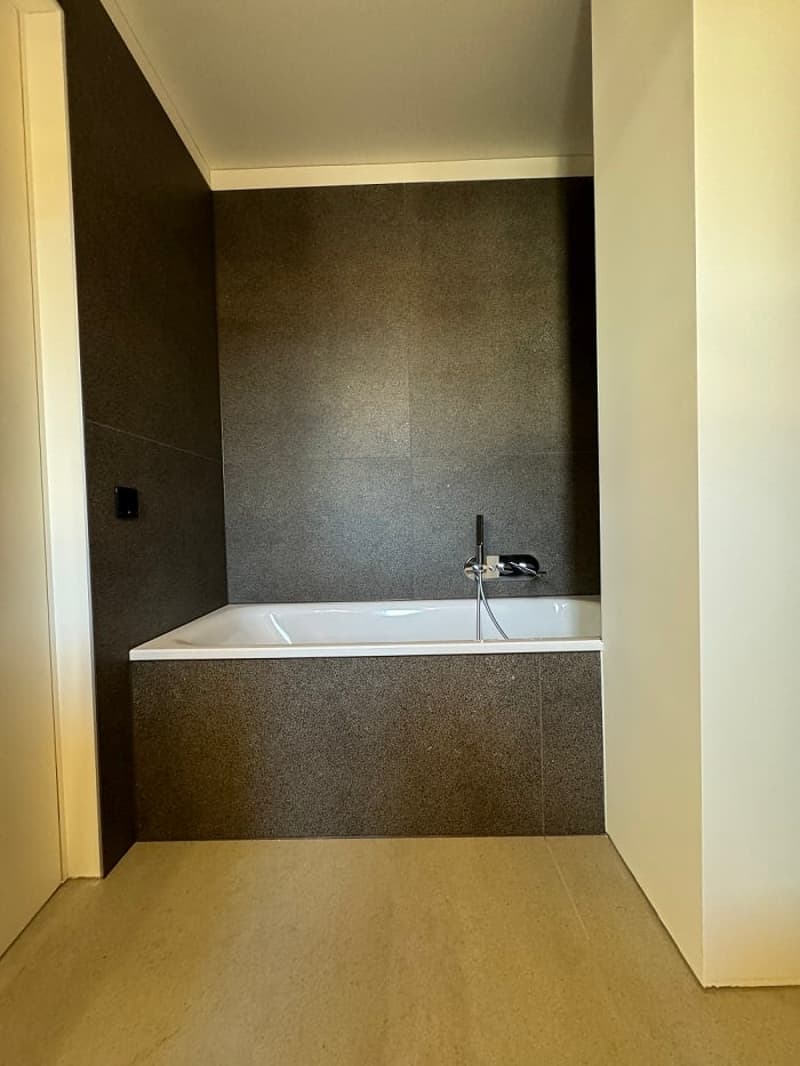 Modern bathroom with integrated bathtub, white tile, dark tile, faucet