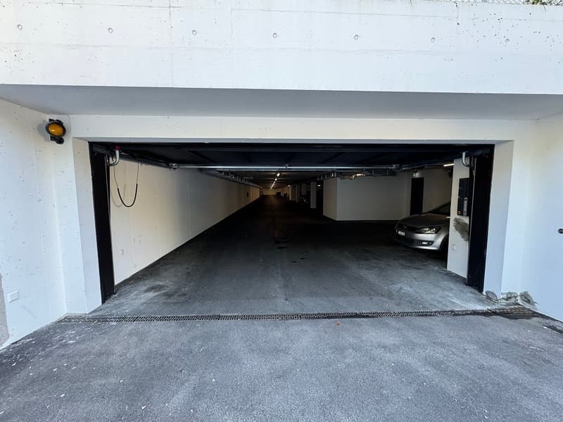 Underground parking garage with concrete floor and white walls. The garage appears to be large enough to accommodate multiple vehicles.