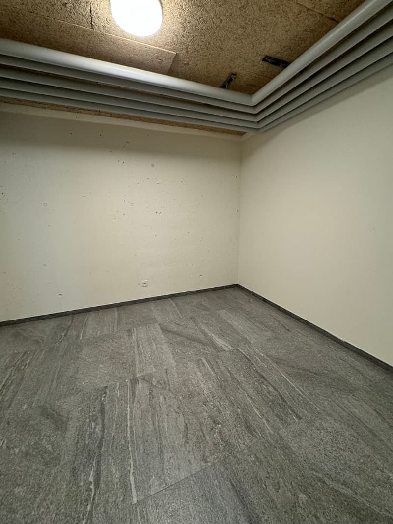 Empty room with white walls, gray laminate flooring, and a recessed lighting fixture in the ceiling.
