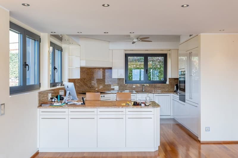 modern kitchen with white cabinets, wooden floor, granite countertops, island with seating, ceiling fan, appliances