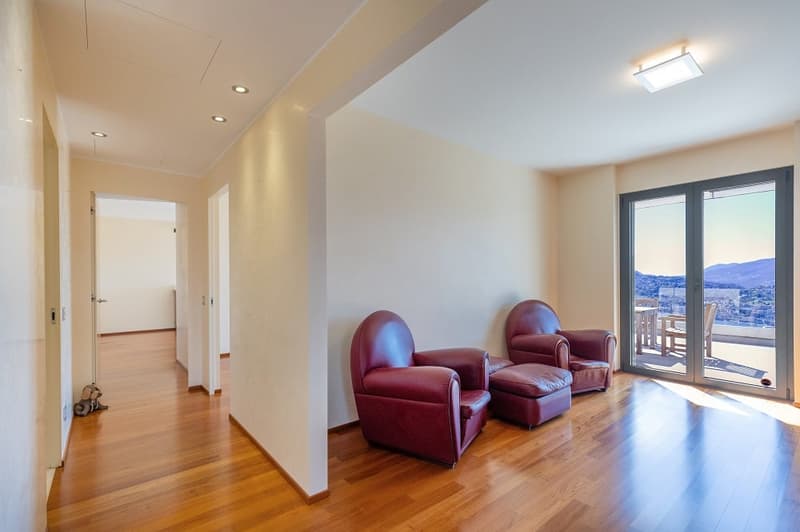 wooden floor, two red leather armchairs, ottoman, sliding glass doors, balcony, city view
