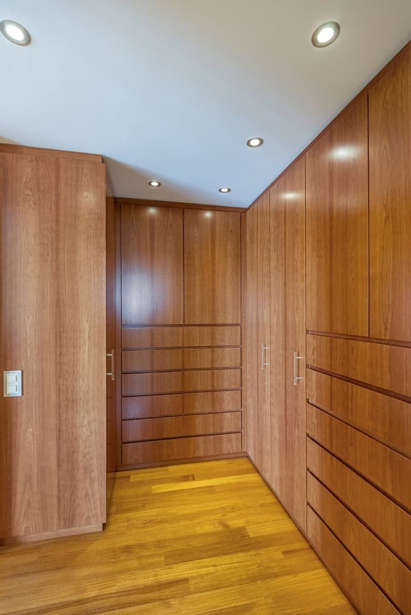 walk-in closet with wooden cabinets, drawers, and wooden floor