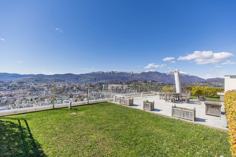 Roof terrace with a view of the city and mountains, wooden planters, outdoor dining set, and a white umbrella