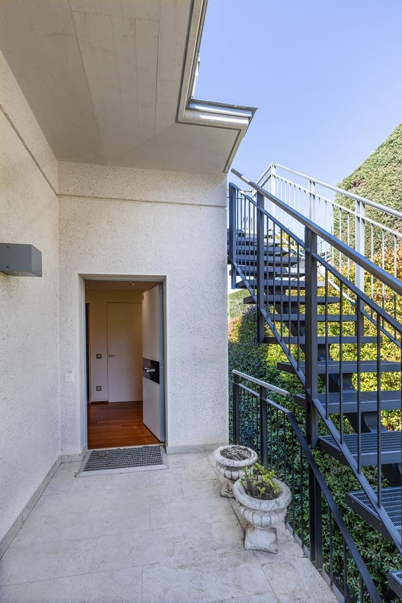entrance with stairs, tiled floor, two potted plants, white door, metal railings