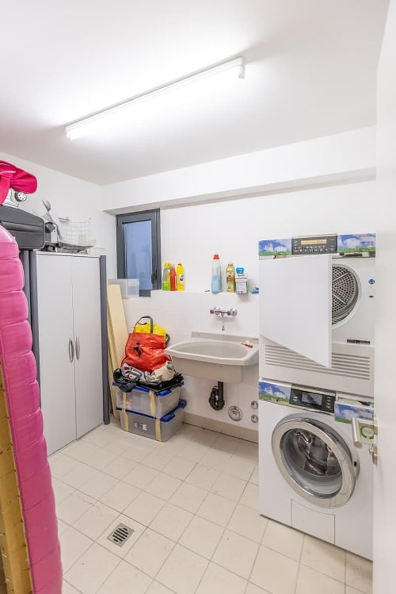 Laundry room with washing machine, dryer, sink, and storage cabinets.