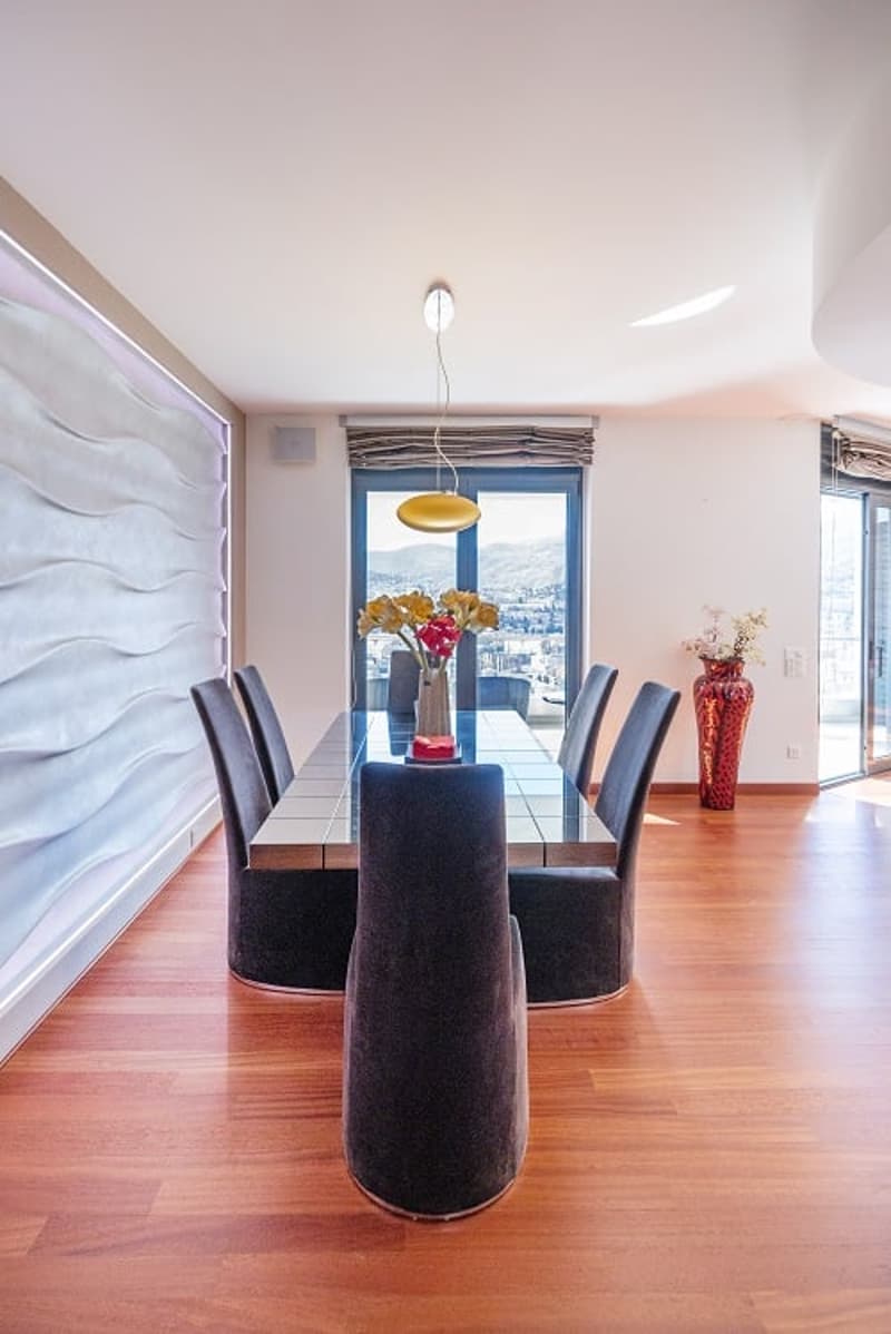 Dining room with wooden floor, large windows, dining table, chairs, flower vases, pendant light