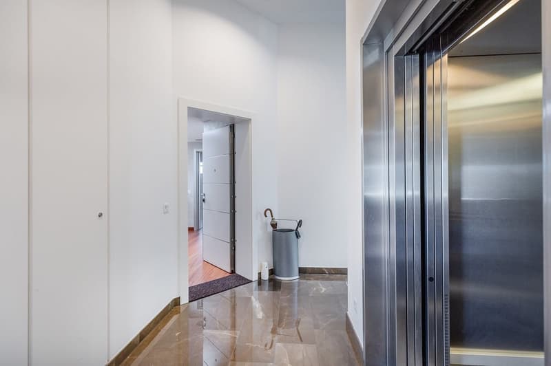 white walls, marble floor, open door, trash bin, umbrella stand, elevator