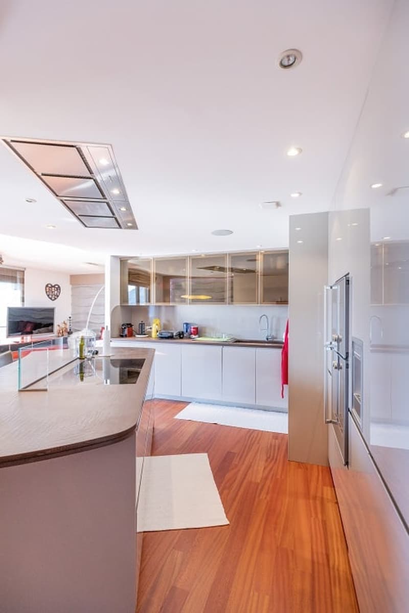 modern kitchen with island, white cabinets, wooden floors, stainless steel appliances, large windows