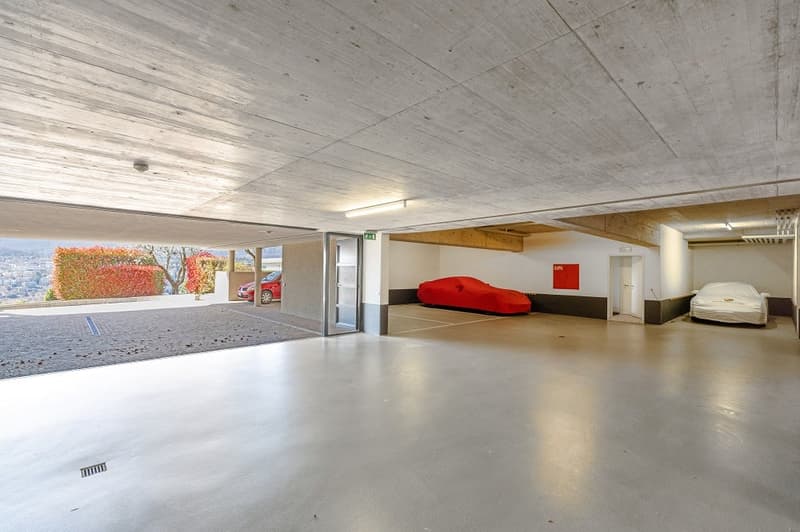 underground parking lot, covered, concrete floor, two cars parked, one car covered