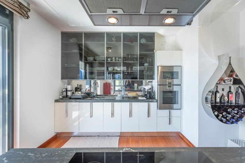modern kitchen with white cabinets, granite countertops, stainless steel appliances, wine rack, wooden floor