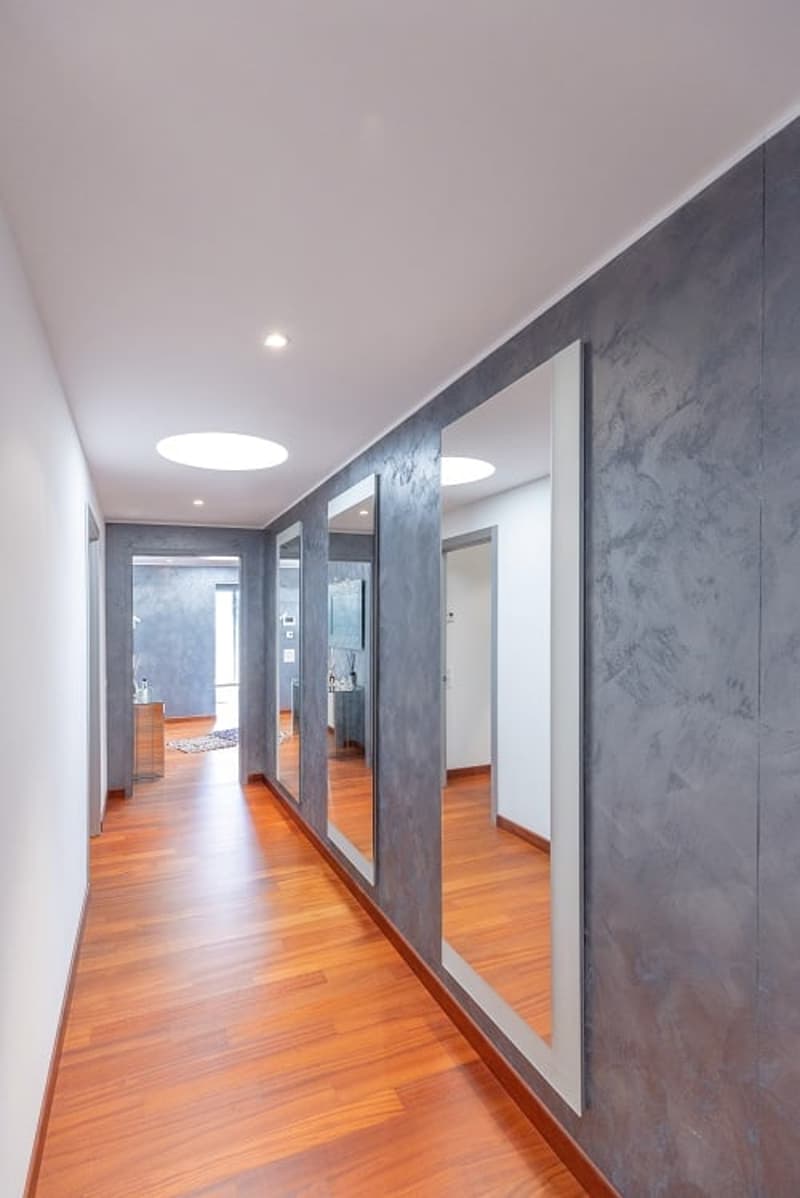 long hallway, wooden floor, gray walls, mirrors, round lights on ceiling