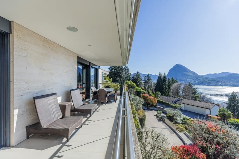Outdoor balcony with seating, table, and scenic view of mountains and water