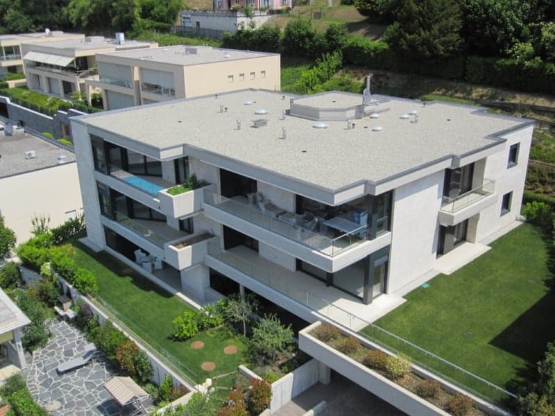 Modern white house, multiple balconies, large windows, green lawn, garden, aerial view