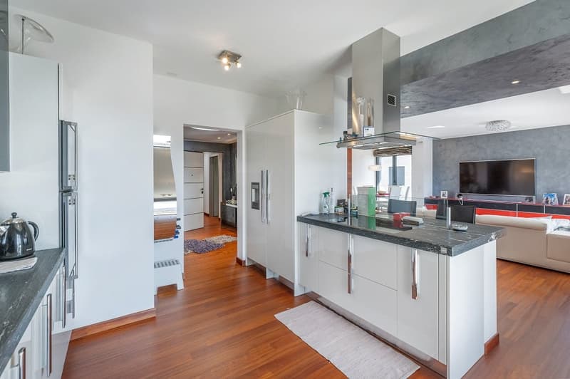modern kitchen with white cabinets, wooden floor, granite countertop, stainless steel appliances, island with seating, open to living room