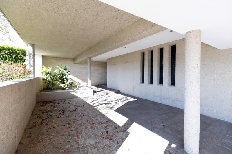 modern house, raised ground floor, concrete walls, brick floor, concrete ceiling, plants