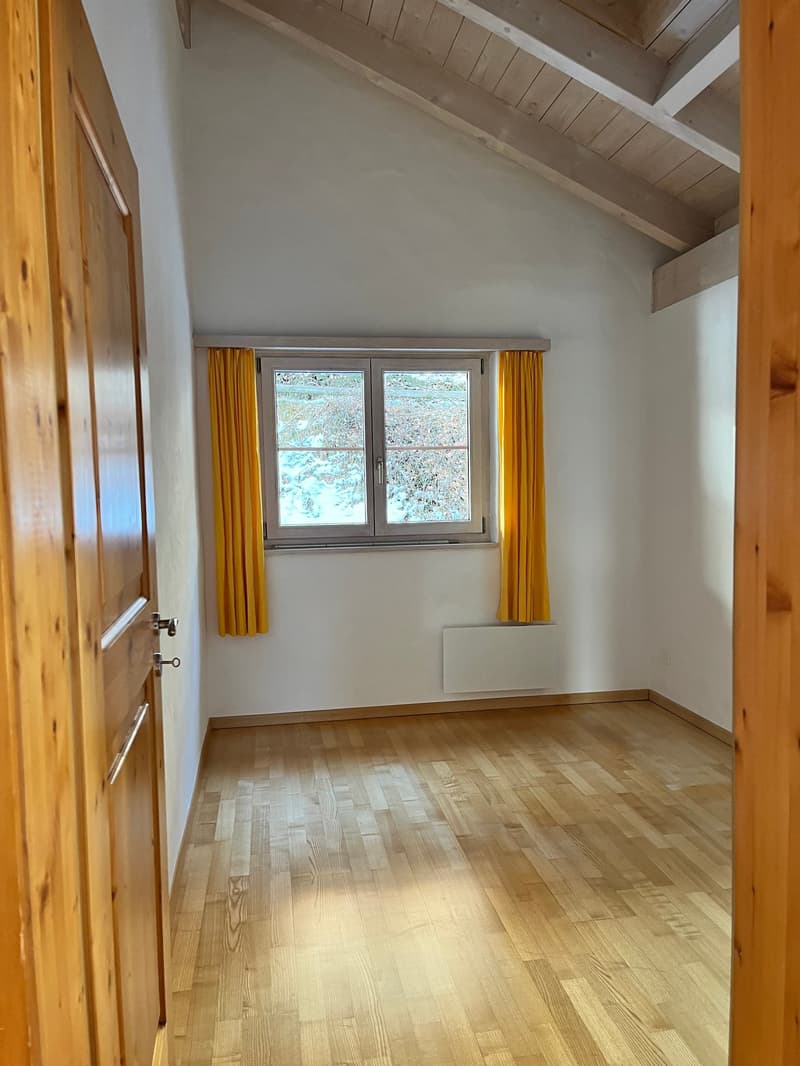 empty room with wooden floors, white walls, window with yellow curtains, wooden door