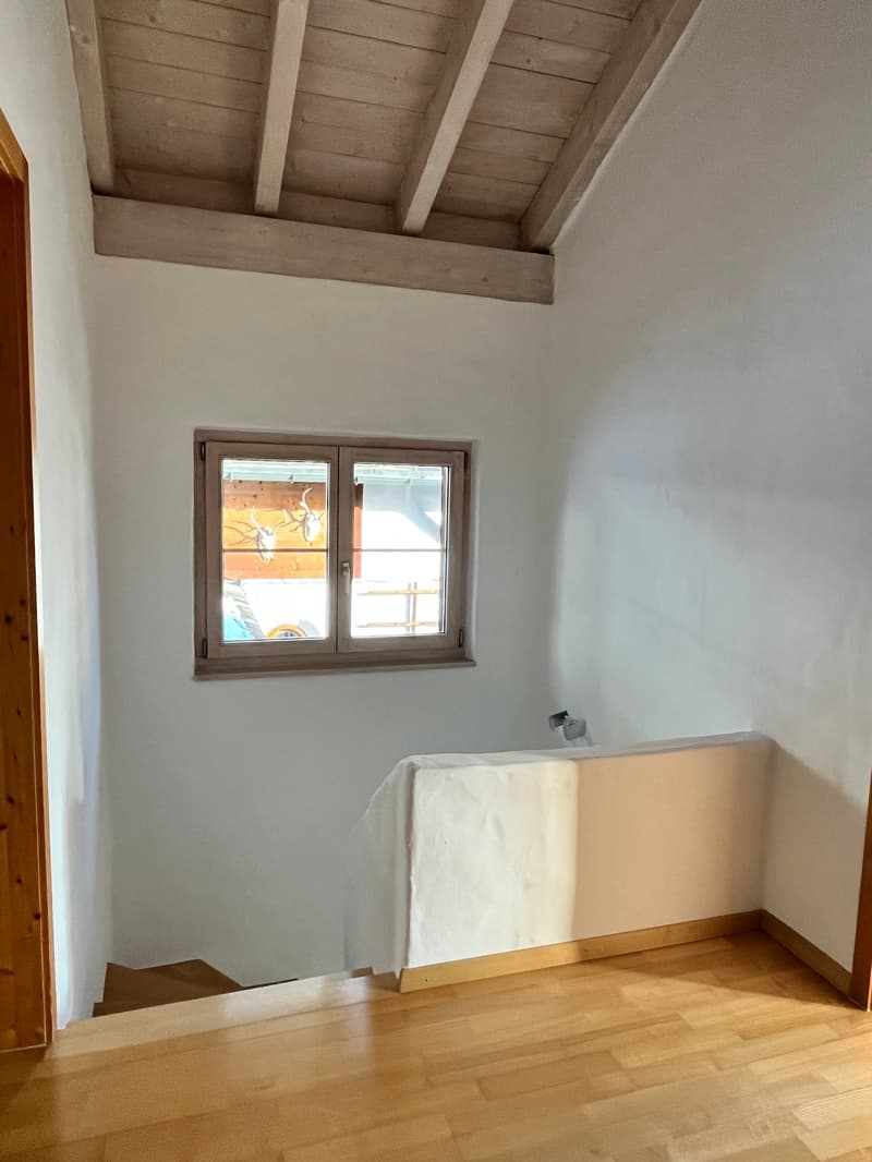 white wall, wooden floor, window, deer head, wall shelf, stairway