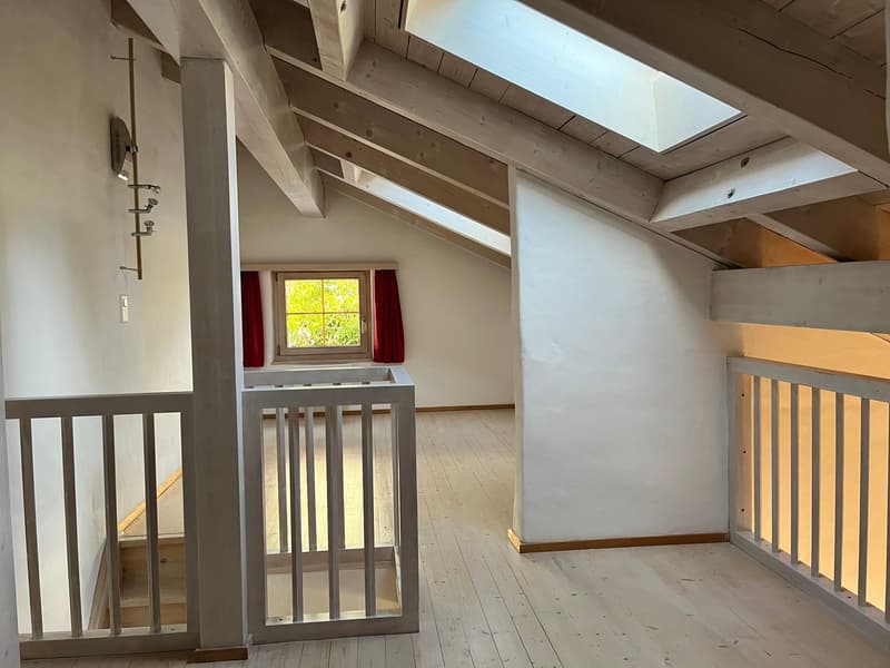 exposed wooden beams, wooden flooring, natural light from window and skylights, staircase