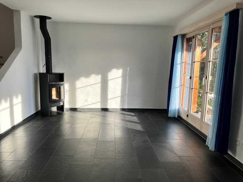Empty room with white walls, black tiled floor, modern fireplace, sliding doors, and outdoor view
