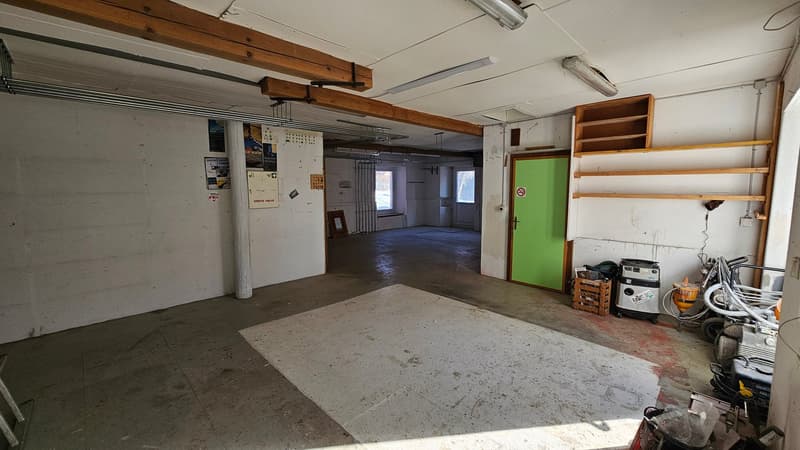 empty garage, concrete floor, wooden shelves, green door, white walls, white ceiling