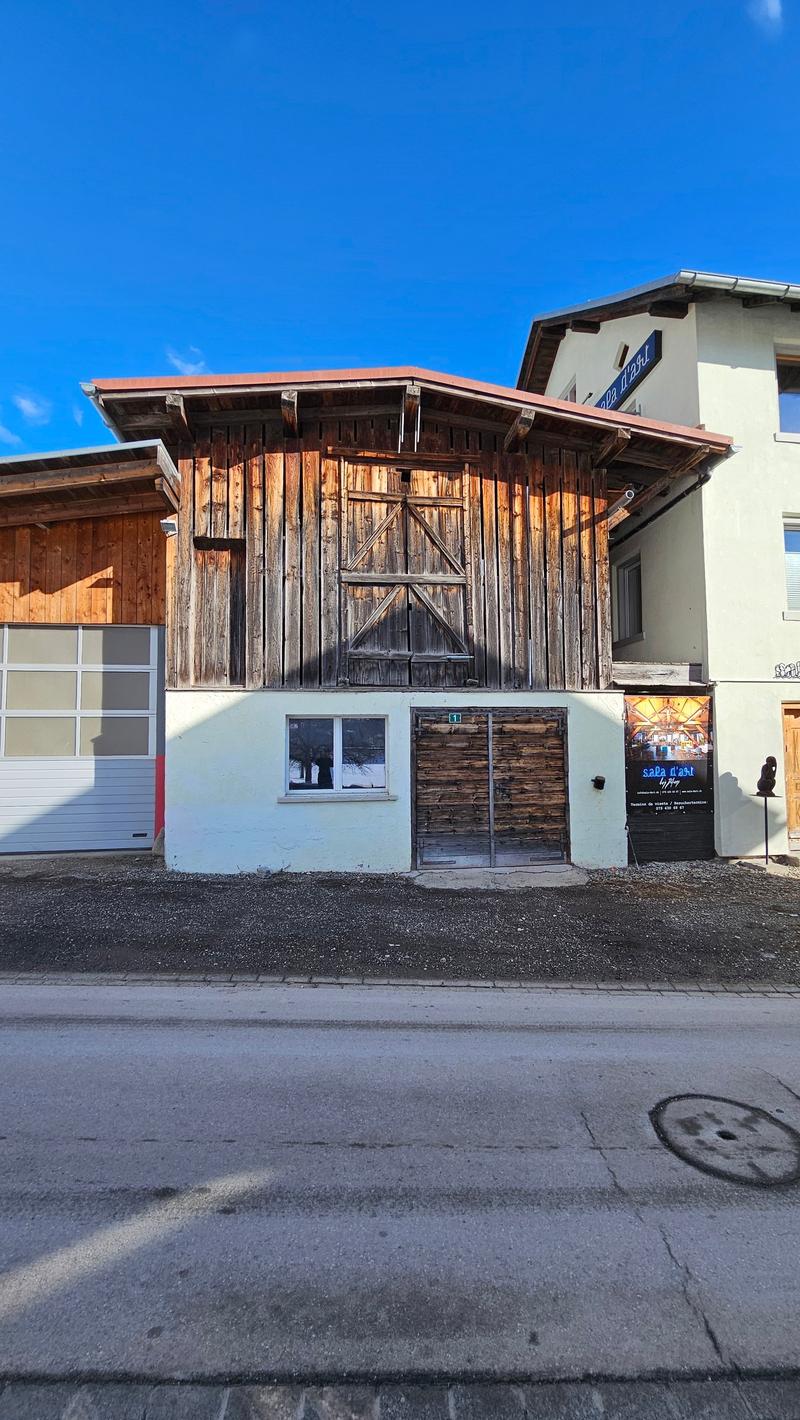 Old wooden house with garage, metal roof, sign on wall