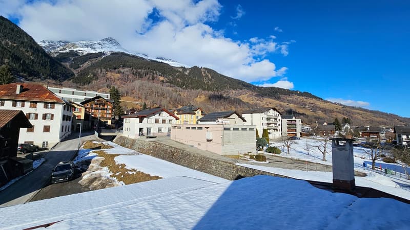 Snowy street with multiple houses and mountains in the background